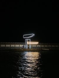 Illuminated bridge over river against sky at night