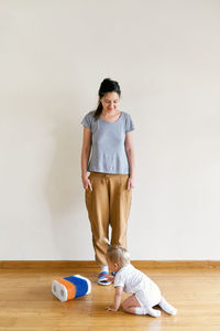 Full length of mother and daughter on floor at home