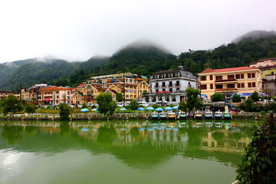 Houses by lake against sky