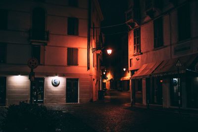 Illuminated street amidst buildings at night