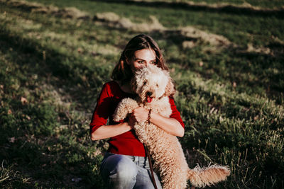 Woman with dog crouching on grass