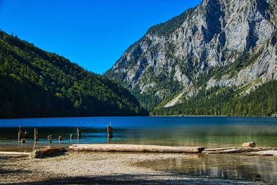 Scenic view of lake and mountains against clear blue sky