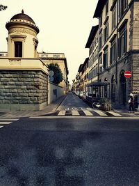 Road by buildings against sky in city