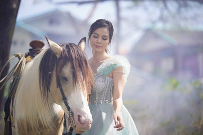 Portrait of a beautiful woman with a horse in the forest background.