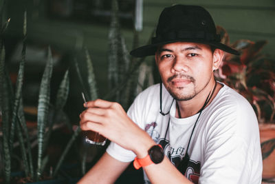 Portrait of young man holding glass outdoors