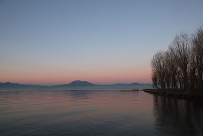 Scenic view of lake against clear sky during sunset