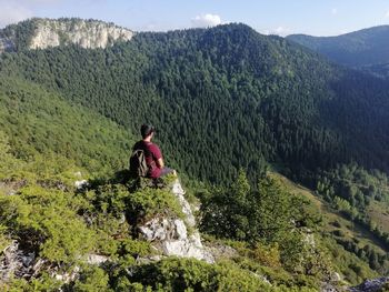 Man sitting on mountain against trees and mountains