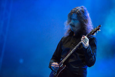 Man playing guitar against blue sky