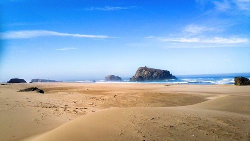 Scenic view of beach against blue sky