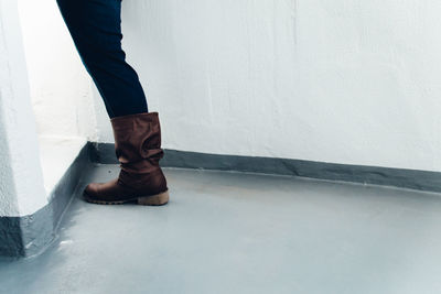 Low section of man standing against white wall