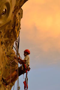 Low angle view of man climbing wall