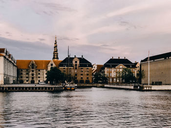 River amidst buildings in city against sky, copenhagen denmark 