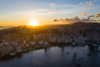 High angle view of river by buildings against sky during sunset