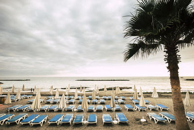 Lounge chairs at beach against sky