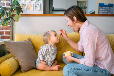 Mom feeds a small child at home with yogurt from a spoon. family concept