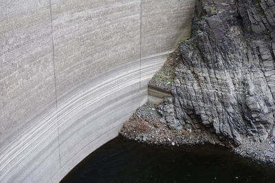 High angle view of water in a dam, with the dam wall and rocks showing water evaporation levels