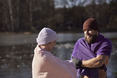 Smiling couple wrapped in towel in lake