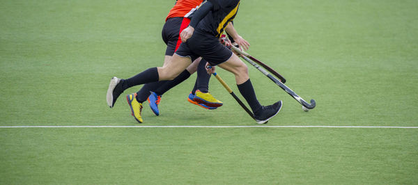 Low section of athletes playing of hockey on field