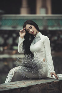 Beautiful young woman sitting on retaining wall