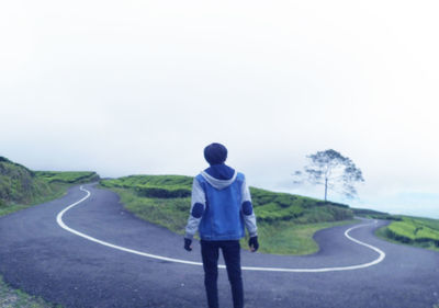 Rear view of man standing on road against sky