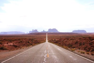 Empty road on landscape against clear sky at monument valley