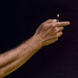 Close-up of man holding hands against black background