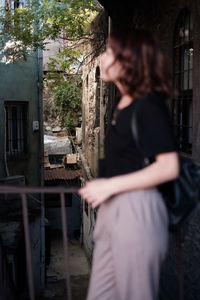 Side view of woman standing by built structure