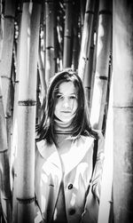 Portrait of young woman standing amidst bamboo grooves