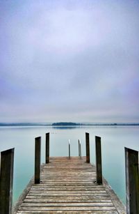 Pier on sea against cloudy sky