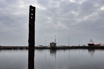 Sailboats on wooden post in lake against sky