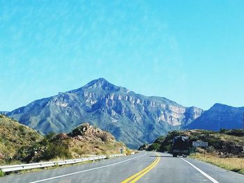 Road by mountains against clear blue sky