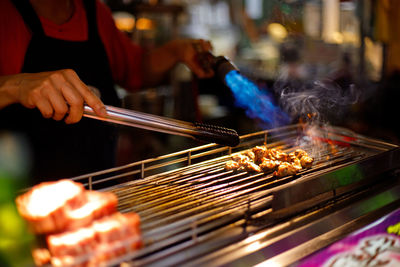 Midsection of person preparing food on barbecue grill