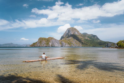 Scenic view of sea by mountain against sky