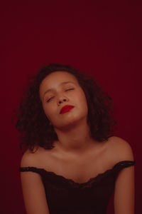 Portrait of beautiful young woman against red background