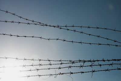 Low angle view of barbed wire against sky