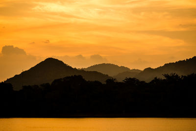 Silhouette mountain with attractive background, sunset with vivid yellow sky and lake