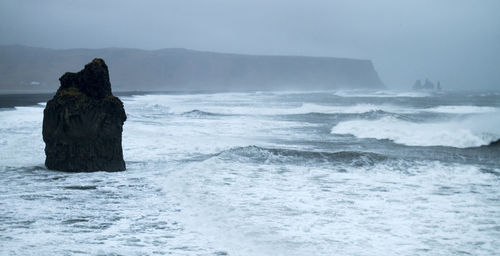 Waves splashing on sea against sky