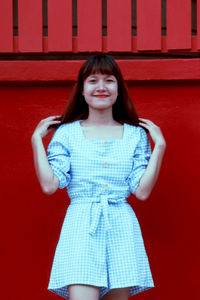 Portrait of smiling girl standing against red wall