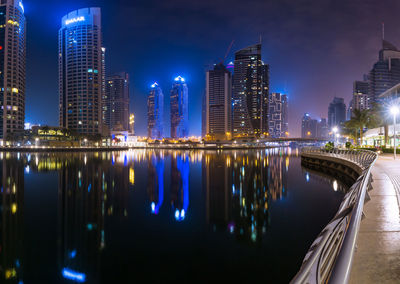 Night city dubai in uae. reflection of illuminated buildings in river at night