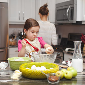 Baby girl with vegetables on table at home