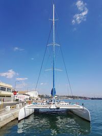 Sailboats moored on sea against blue sky