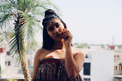 Young woman with arms raised standing against sky