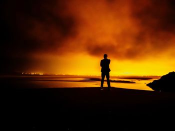 Silhouette man standing on beach against sky during sunset
