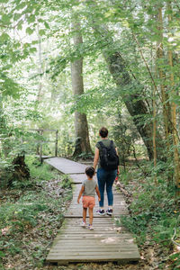 Full length of mother and daughter walking in forest