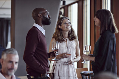 Male and female colleagues talking while enjoying drinks in party after work