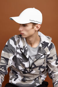 Portrait of young man wearing hat against gray background