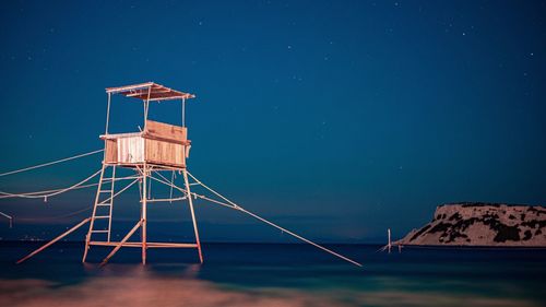 Lifeguard hut by sea against blue sky