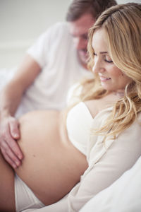 Man touching pregnant woman's stomach in bed