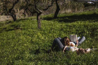 Two young girls lying in the field read a book