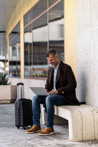 Man using smart phone while sitting in laptop